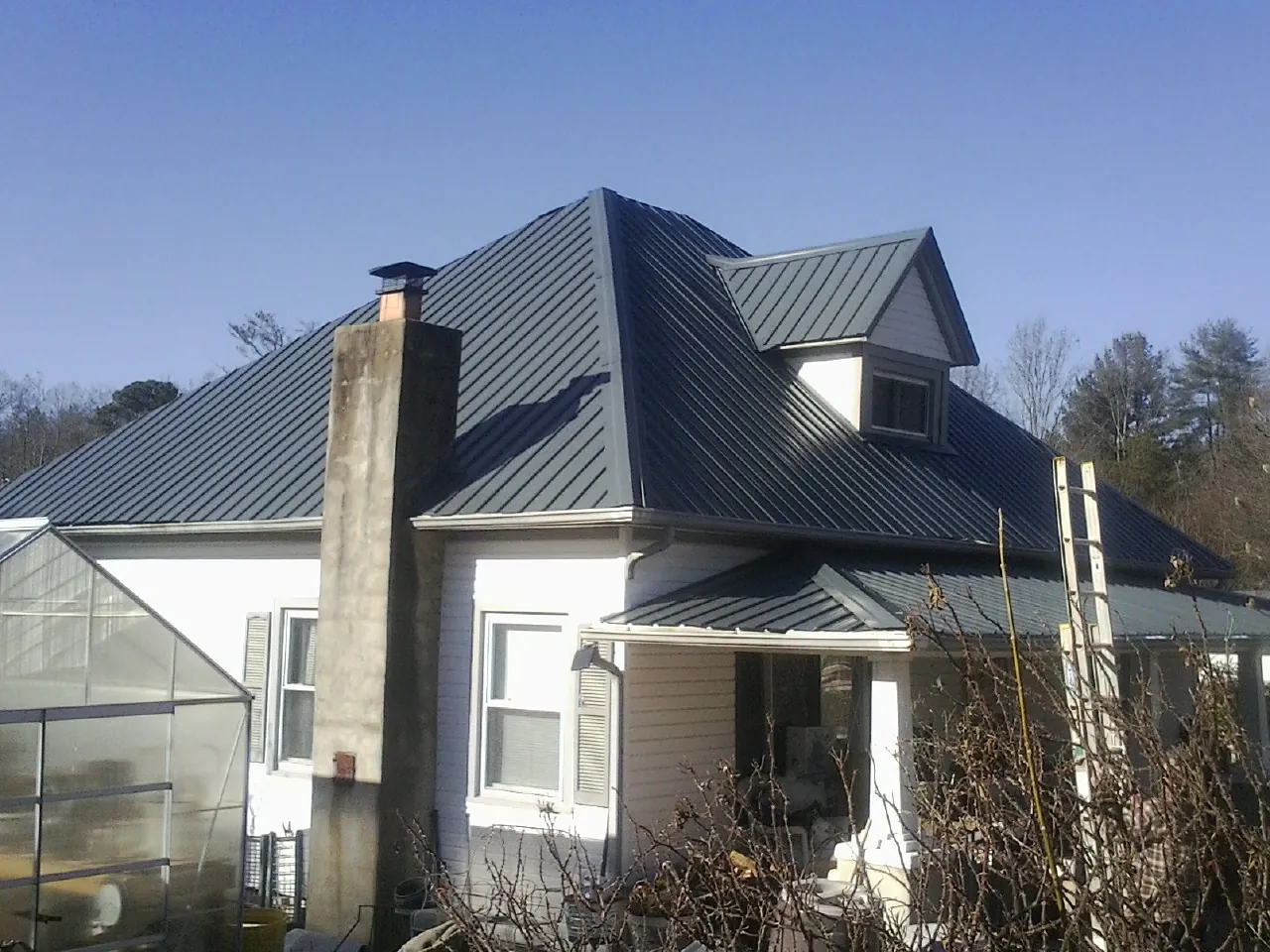 Dark blue standing seam metal roof on a white farmhouse with dormer — Slate & Tile Roof Repair by Roofing Brothers in Warren