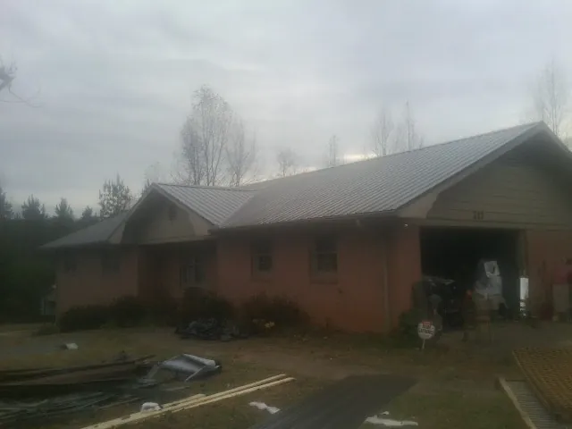 Gray metal roof on a stucco house with an attached garage in Warren