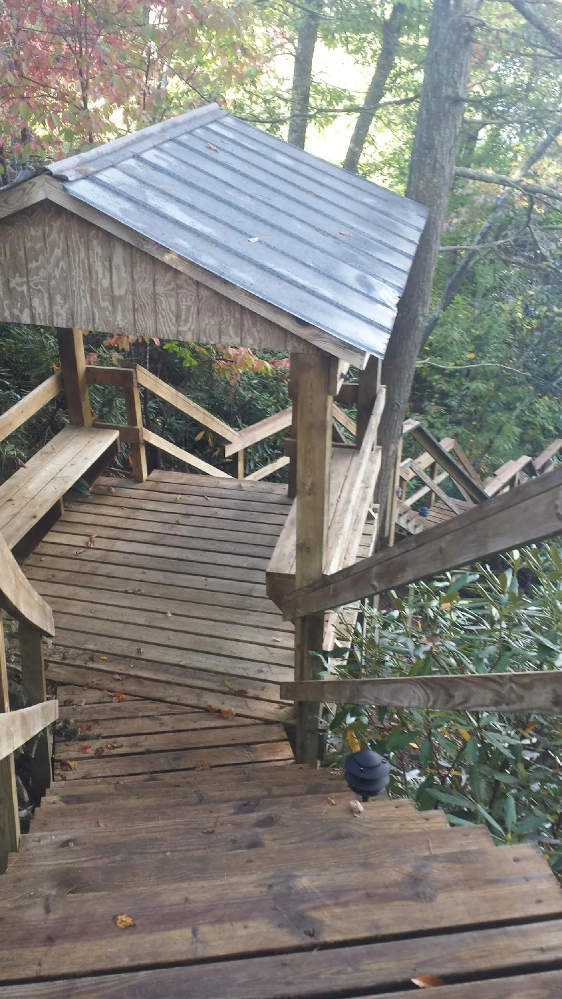 Metal roofed shelter over wooden steps on a wooded walkway — Skylight Repair & Installation work by our crew in Warren